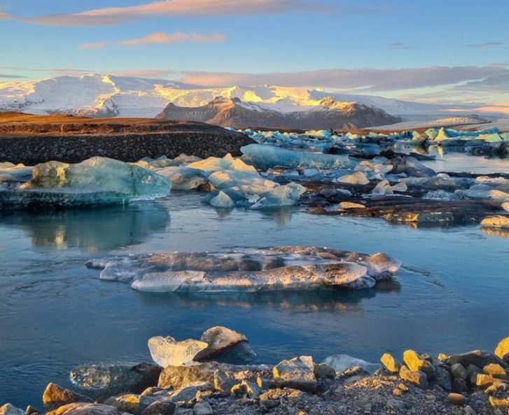 Ice bergs shining in the sunset light with mountains in the background.