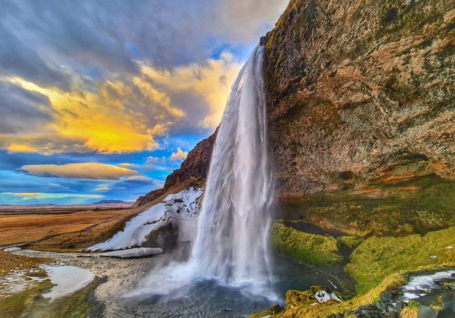 Seljalandsfoss waterfall during a spring day with a colorful sky.