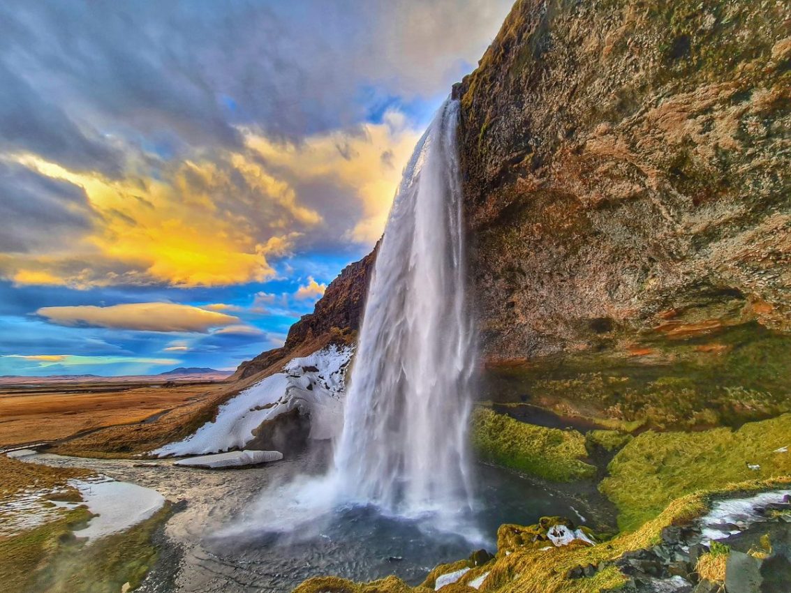 Seljalandsfoss waterfall during a spring day with a colorful sky.