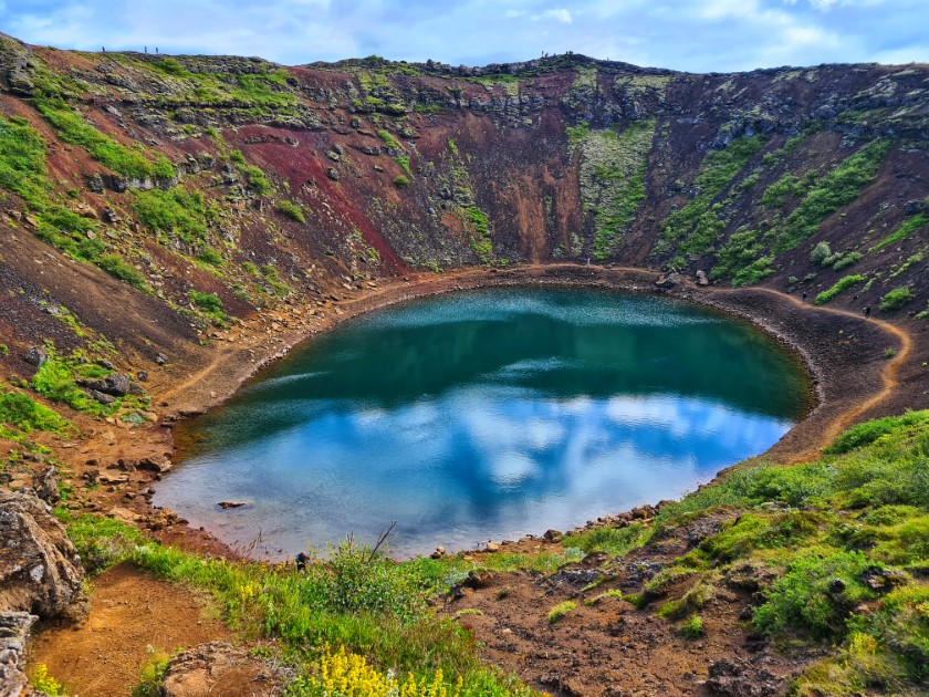 Volcanic crater with mossy walls and a blue lake.