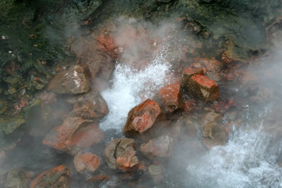 Steamingly hot water coming out between rocks.