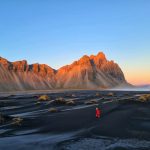 Walking on the Stokksnes beach with Vestrahorn mountain warmed by the sunset light.