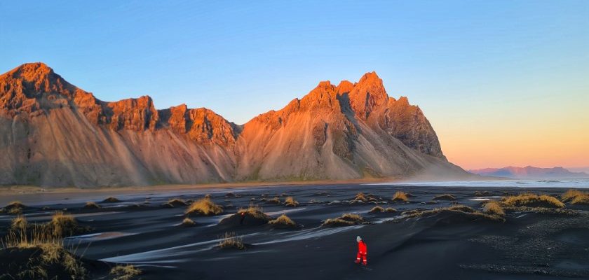 Walking on the Stokksnes beach with Vestrahorn mountain warmed by the sunset light.