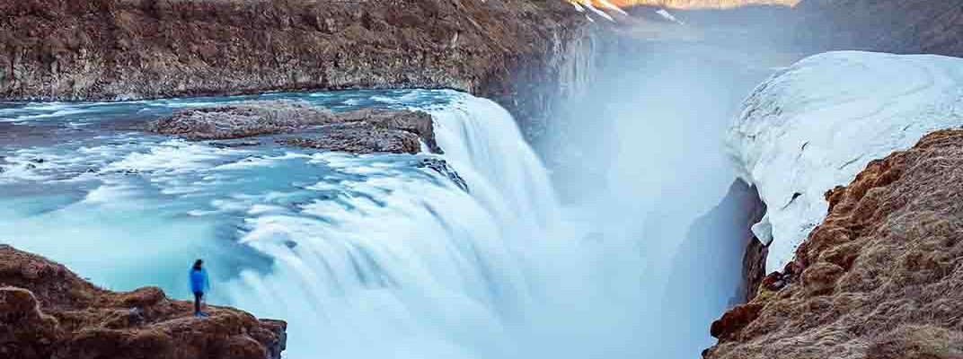 Person looking at Gullfoss waterfall flowing fast.